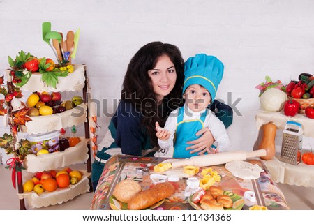 adorable baby cooking in kitchen with mother . little cute child in costume of Cook. Pretty beautiful boy covered in flour makes cakes.baby boy