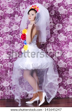 Gorgeous sexy bride in luxury wedding dress with hairstyle and makeup in interior. Fashion shot of alluring happy brunette woman in bridal dress with flowers.Girl  have final preparation for wedding