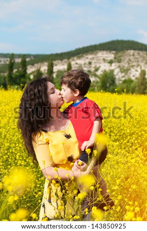 Happy family with child -beautiful mother hug with her son,resting in blossom spring garden with field flowers on nature looking happy smiling outdoors.Smiling girl with healthy hair on nature