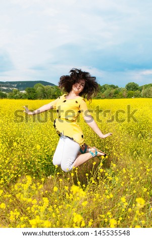 Happy beautiful woman resting in blossom spring garden with field flowers on nature looking happy smiling outdoors. Brunette girl on grass in park enjoying life. Indian woman with glossy healthy hair