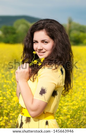 Happy beautiful woman resting in blossom spring garden with field flowers on nature looking happy smiling outdoors. Brunette girl on grass in park enjoying life. Indian woman with glossy healthy hair