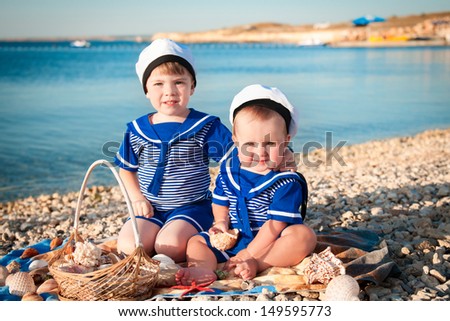 happy small children in a suit of the seaman smiling and having fun on the sea. adorable cute kids playing and resting on nature. trendy funny children on nature enjoying the sun in park and posing