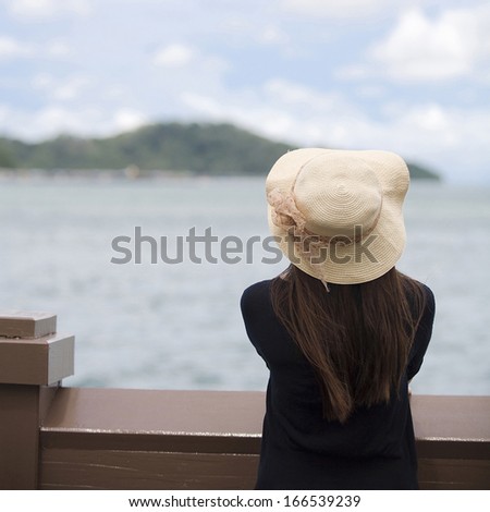 young woman looking at the sky at the seaside