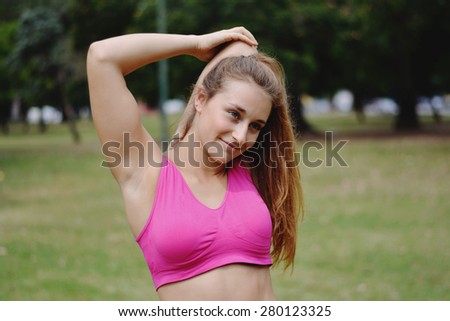 Young woman stretching in the park before Exercise. Caucasian sport fitness model in city park outdoors.