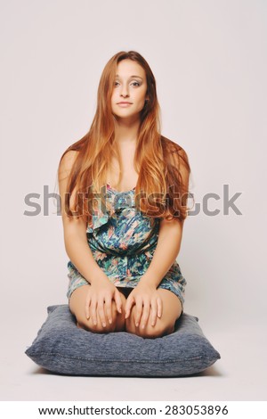 Young Beautiful woman sitting on a cushion over a plain background
