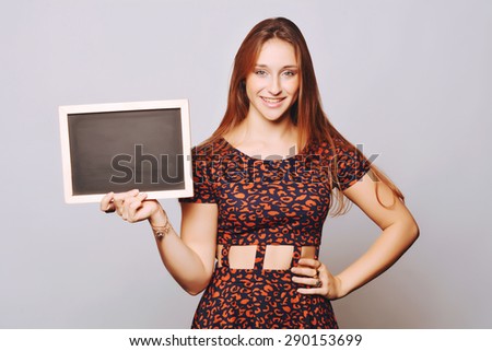 Beautiful young woman holding and showing something on a chalkboard