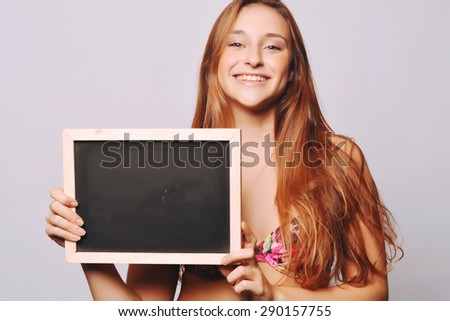 Beautiful young girl holding a chalkboard, isolated over plain background.
