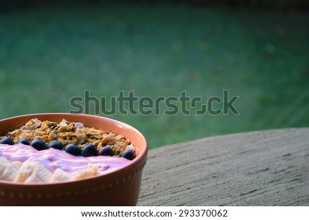 Orange bowl of muesli with banana, berries and yoghurt. Healthy breakfast.