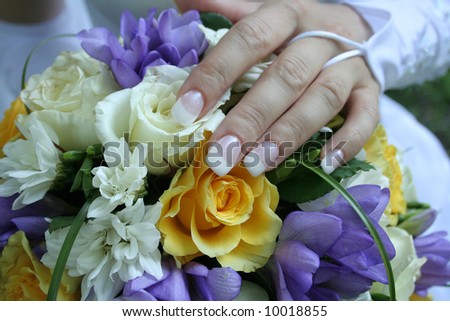 gentle hand of the bride lays on a bouquet