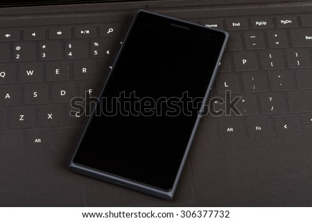 Modern smart cell phone on flat keyboard, business concept