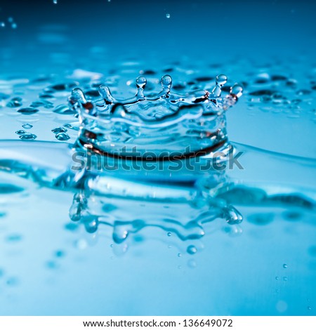 Water splash with suspended droplets in clean fresh pure blue water with a reflection