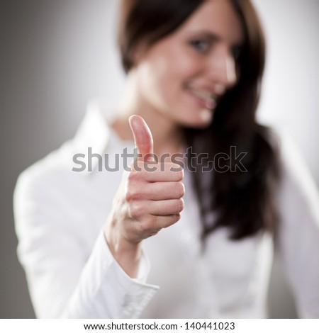 Brunette shows a thumbs-up in approval. Sharp hand and strong bokeh in the models body and face