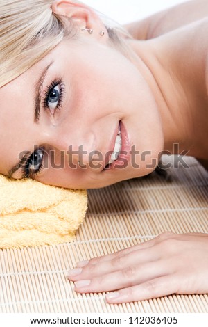 Closeup facial portrait fo a beautiful woman at a spa lying on her stomach with her head resting on a rolled yellow towel