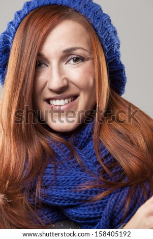 Close-up portrait of a beautiful redhead woman wearing winter clothing like a shawl and a beanie hat