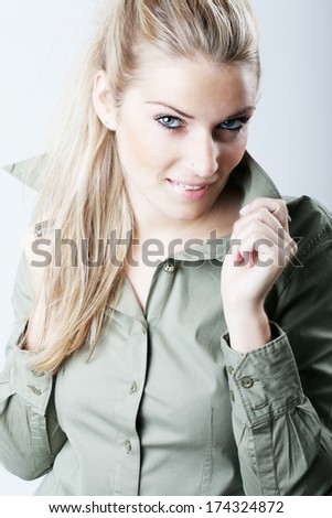 Beautiful stylish woman with long blond hair holding the collar of her blouse and looking up at the camera with a sultry look
