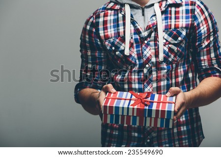Man in Checkered Top Holding Present with Stripe Design. Captured with No Face. Isolated on Gray Background.