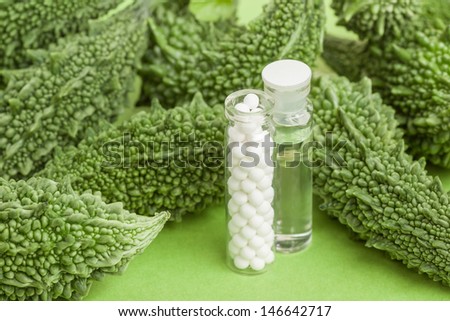 Homeopathy and Bitter Gourd - A homeopathy concept with homeopathic medicine (sugar/lactose pills and liquid homeopathic substance) pictured along with bitter gourds which have homeopathic uses.