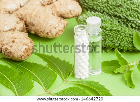 Homeopathy - A concept with homeopathic medicine (sugar/lactose pills and liquid homeopathic substance) pictured along with homeopathic vegetables and herbs (ginger, bitter gourd, neem, basil).