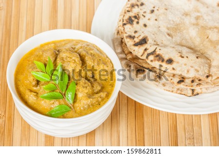 Indian Mutton Curry and Chapati - Closeup view of delicious mutton curry served with fluffy chapati (Indian bread). Curry prepared using onions, curry leaves, garlic, ginger, cayenne & black pepper.