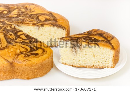 Marble Cake Slice - A closeup view of a marble cake and a slice of it. The marble cake is similar to a pound cake but has random chocolate swirls on it.