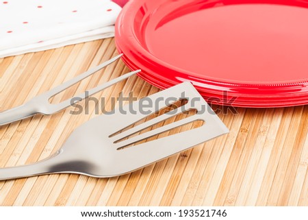 Barbecue Time - A set of barbecue tools and plastic plates on a bamboo mat symbolizing barbecue time.