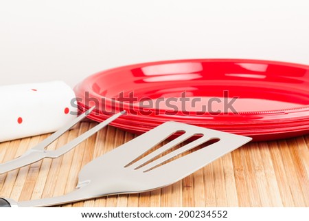 Barbecue Time - A set of barbecue tools and plastic plates on a bamboo mat symbolizing barbecue time.
