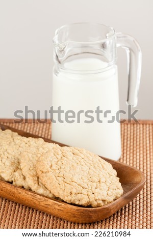 Oatmeal Cookies - A set of fresh, homemade oatmeal cookies on a wooden tray served with milk. Shallow Depth of Field.