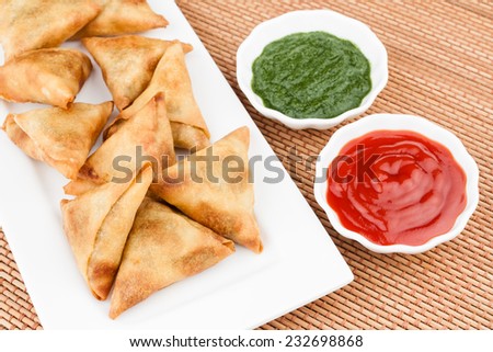 Samosa with Mint Chutney - Overhead view of delicious deep fried south Indian samosa with mint chutney and tomato sauce.