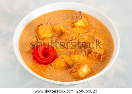 Closeup of delicious Indian paneer butter masala garnished with tomato peel. It is prepared using paneer (cottage cheese), butter, tomato and various spices.