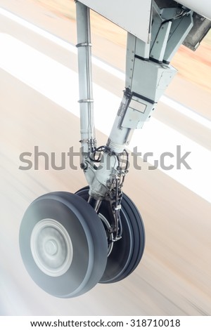 Landing gear during takeoff - The landing gear of an aircraft captured at the moment of takeoff against a blurred runway.