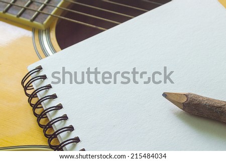 Notebook and wooden pencil on guitar,Writing music