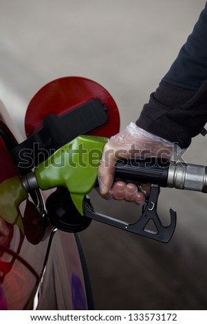 Refueling. Close-up of a man\'s hand using plastic globe to fill his car up with fuel.