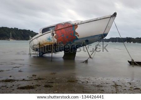 Sailboat abandoned.  Graffiti on a sailboat stranded in sand and abandoned at low tide near Saint Malo, Brittany, France