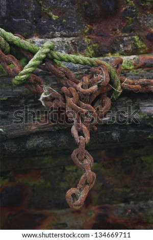 Old rusty chain. Abandoned old boat detail. Old rusty chain tied to a green cord