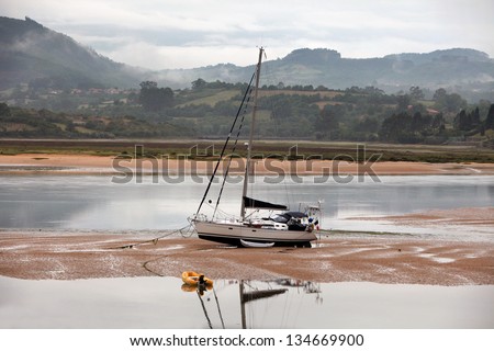 Boat stranded in sand.  Sailboat stranded at low tide in Ria of Villaviciosa, Asturias, North Spain.