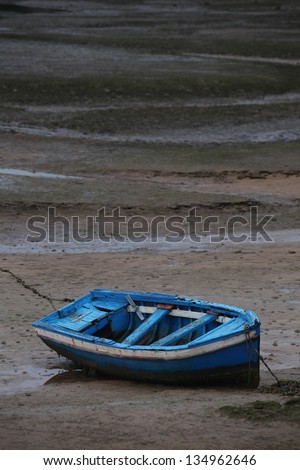 Barque at low tide. Blue old barque stranded in beach at low tide. Asturias, North Spain.