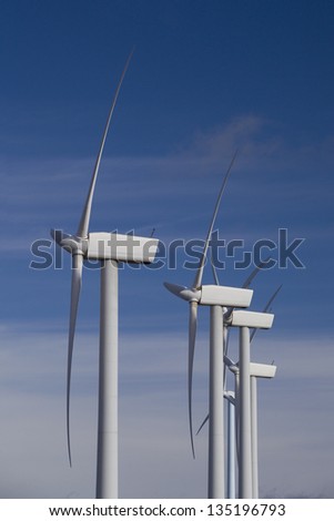 Wind turbines. Vertical view of several wind turbines in blue sky