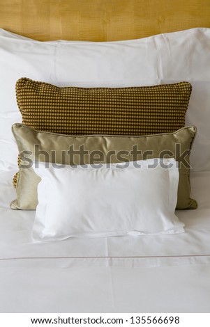 Pillows on a bed. Three cushions sorted by colors on a big bed