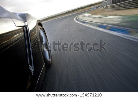 Low angle shot from the side of a car driving in a curve in a racetrack. Car running in a racetrack.