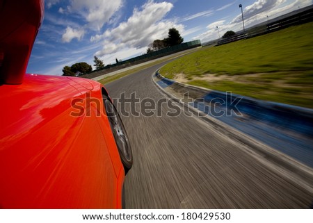 Low angle shot from the side of a car driving in a curve in a racetrack. Red car running in a racetrack.