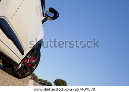 View of the wheel of a withe sport car on a road with blue sky on the background. 
Wheel on a road