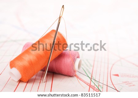 Spool of thread and needle. Sew accessories on blurred background.
