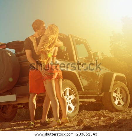 A couple kissing next to a 4x4 car on sunset