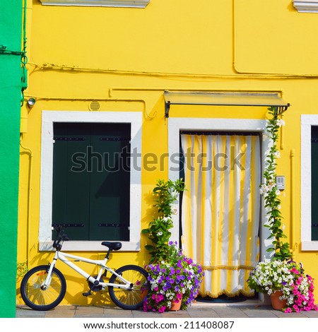Colorful houses in Burano with a bike standing next to a flower decorated door