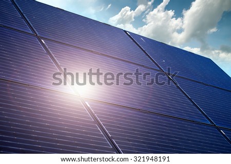 Solar battery panel against blue sky with sun reflection