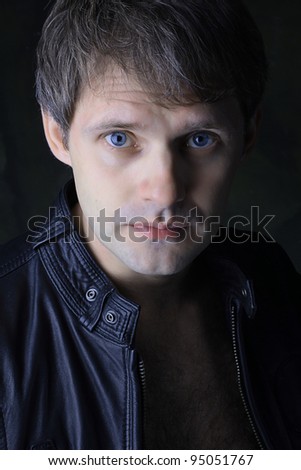 attractive male in black leather jacket in front of dark background