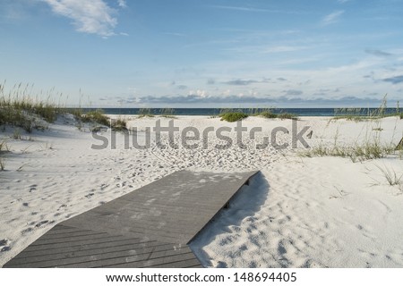 Beach boardwalk footpath meets the sand on beautiful Gulf Coast beach in the early morning.
