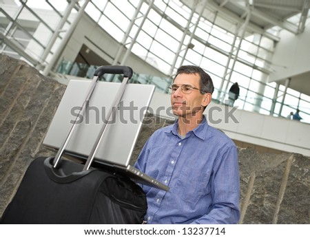Man working on his laptop computer in Seattle airport terminal, laptop propped on his suitcase