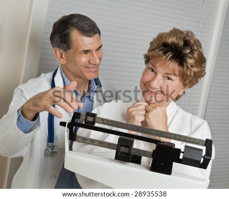 Doctor with smiling woman who has reached her target weight on medical scale in doctor\'s office.