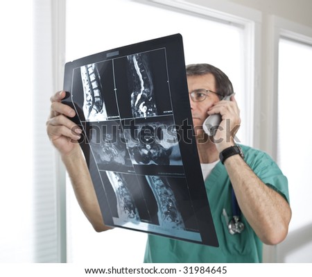 Doctor looking at radiology scan. Short depth of field. Focus on MRI/Xray film. Doctor out of focus.